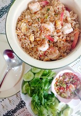 Chinese style fried rice with shrimp and egg served with fresh vegetables cucumber and parsley and famous Thai style dipping fish sauce with bird eye chili, onion and lemon or lime. Delicious food.