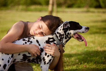 a young girl plays with a dalmatian in the park. dog care concept