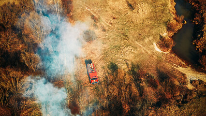 Aerial View. Spring Dry Grass Burns During Drought Hot Weather. Bush Fire And Smoke. Fire Engine, Fire Truck On Firefighting Operation. Wild Open Fire Destroys Grass. Ecological Problem Air Pollution.