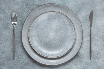 Empty gray plates with cutlery on a gray concrete background. Top view, flat lay.