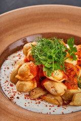 Close-up of a plate of Turkish manti with herbs and yogurt