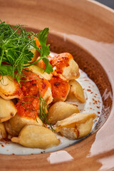 Close-up of a plate of Turkish manti with herbs and yogurt