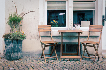 Wooden table and chairs in front of an old appartment