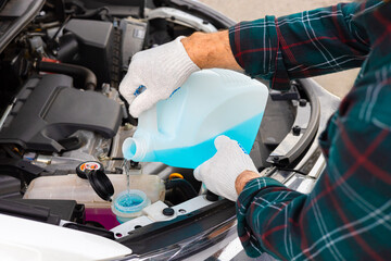 the driver pours antifreeze into the car - obrazy, fototapety, plakaty