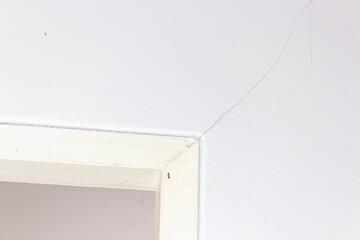 White wall and wood frame with crack in the white wall background.