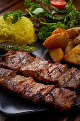A plate of grilled kebab meat with potatoes and rice