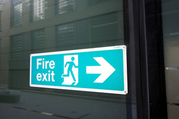 fire exit sign in blue on a glass building 
