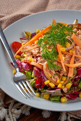 Close-up A plate of tuna salad with carrots and tomatoes on a wooden floor