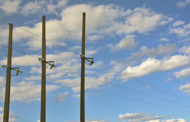 Concrete pole with wires of power line against the background of blue cloudy sky