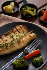 A plate of mackerel with boiled vegetables on a wooden floor