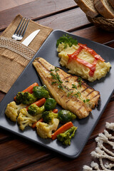 A plate of mackerel with boiled vegetables on a wooden floor