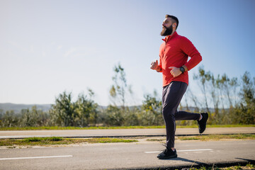 Adult man is jogging outdoor on sunny day.