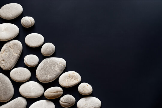 stones on black background. white stones pebbles in a minimalist style close-up, pattern in the corner. wallpaper and background concept