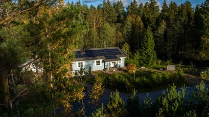 Aerial view of a detached home powered by photovoltaic cells, sunny autumn day