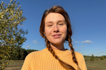 Portrait of happy positive young woman outdoors at park of forest at autumn sunny day 