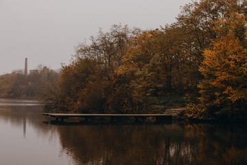 Wooden fishing pier over the autumn pond in the morning