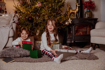 Two little happy girls in pijamas with gift boxes on christmas new year's eve