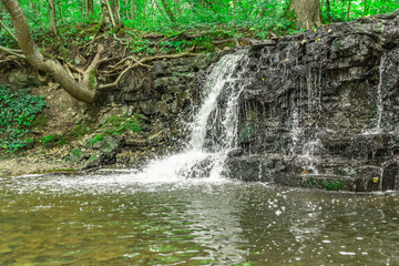 A small waterfall in the middle of the forest between dolomite rocks