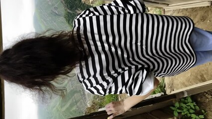 a girl leaves the house to a beautiful view in the mountains, a woman looks at huge rocks, vertical video footage - Powered by Adobe