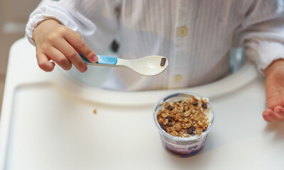 baby's chubby arms grasping a spoon, eating nutritious baby food, symbolizing essential child development and nurturing care, with blurred background