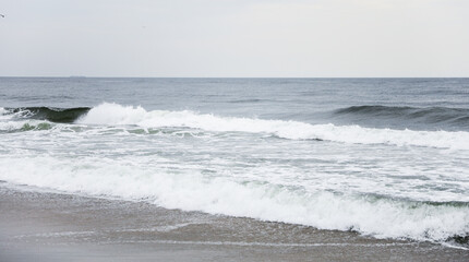 beach waves, a soothing symphony of nature's power and serenity, crashing on a sandy shore under a clear blue sky