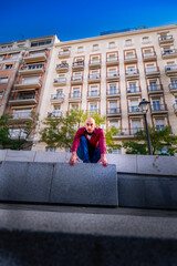 Concentrated bald guy readies for parkour flips in Madrid's cityscape.