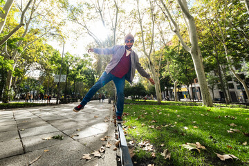 Street balancing act: Young man, wide-angle lens, showcases poise in autumn Madrid.