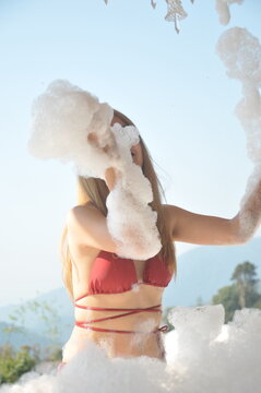 Young woman wearing bikini red color relaxing washing in bathtub. rear view
