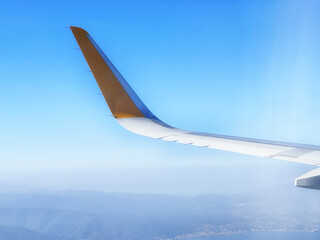 Airplane wing high up in the blue sky over the bay and the city. Travel and transportation...