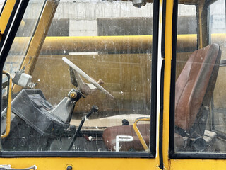 Detailed view of dirty excavator cabin with steering wheel and seat and controls. Industrial...