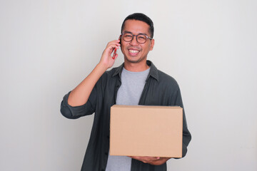 Adult Asian man smiling when calling and holding a package box