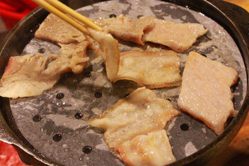 Grilled pork being grilled on a hot griddle.