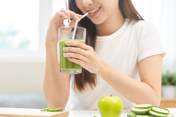 Green detox juice concept, Beautiful asian young woman holding vegetable smoothie glass with straw...