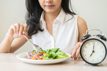 Intermittent fasting with clock, health asian young woman, girl weight loss, eating green fresh...