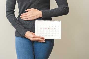Menstruation, periods cycle day of monthly, hurt young woman, female hand holding, marking symbol on calendar for missed and delay or late. Medical, healthcare, gynecological concept, copy space. - obrazy, fototapety, plakaty