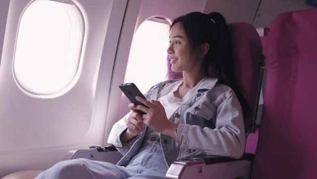 Asian female tourists are currently traveling by plane and exploring their trip through a mobile phone, capturing joyful and impressive moments, providing captivating images of this happy.