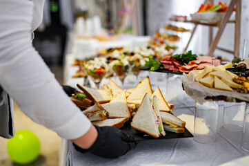 hand of a waiter hold plate with food for a buffet table in a restaurant