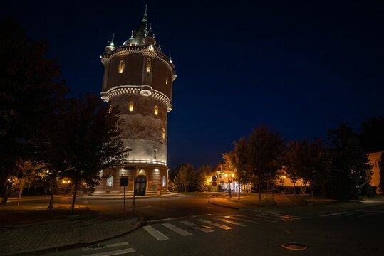 a lit-up tower sits behind a quiet street in the town: Water castle Drobeta-Turnu Severin Romania
