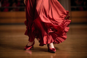 Pies de bailarina de flamenco en zapatos burdeos, vestido rojo vibrante, captura movimiento y pasión