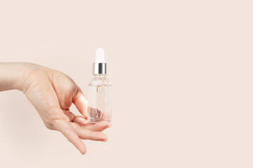 serum in a bottle in a woman's hand on a beige background