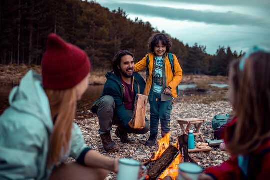 Father and son setting up campfire for the night. Young family camping in the woods together