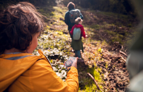 Back view boy using compass on family hike in nature