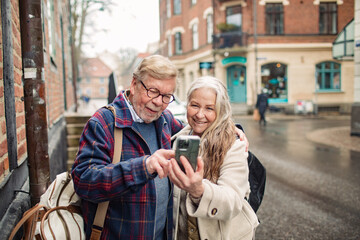 Senior couple using smartphone for navigation on vacation in the city