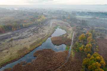Aerial view of the river flowing through the reeds in the foggy morning