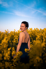Fototapeta premium schöne Frau mit blauem Sommerkleid in einem Rapsfeld