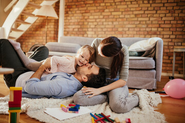 Loving young family playing on living room floor