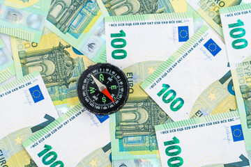  Compass placed over euro banknotes, 100 euro money bills, moving in the right direction