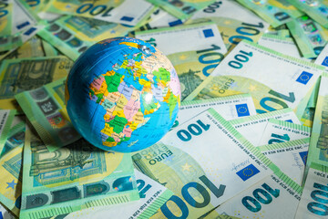 A globus over many money bills with background of 100 euros - obrazy, fototapety, plakaty