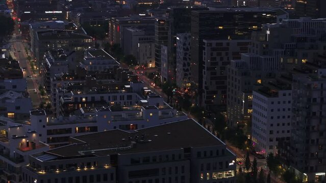 Fly above evening city. Revealing wide boulevard with road, tram tracks and trees in modern residential urban borough. Oslo, Norway