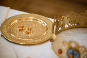 Wedding rings stand on a tray in the church for consecration with water.